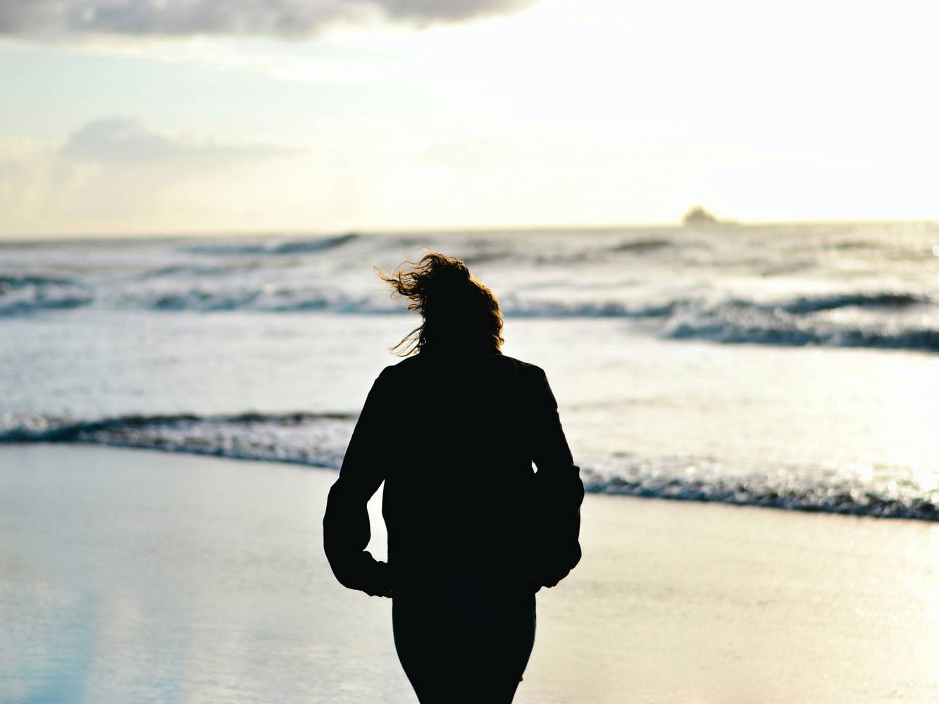 Silhouette einer Frau am Strand bei Sonnenuntergang.